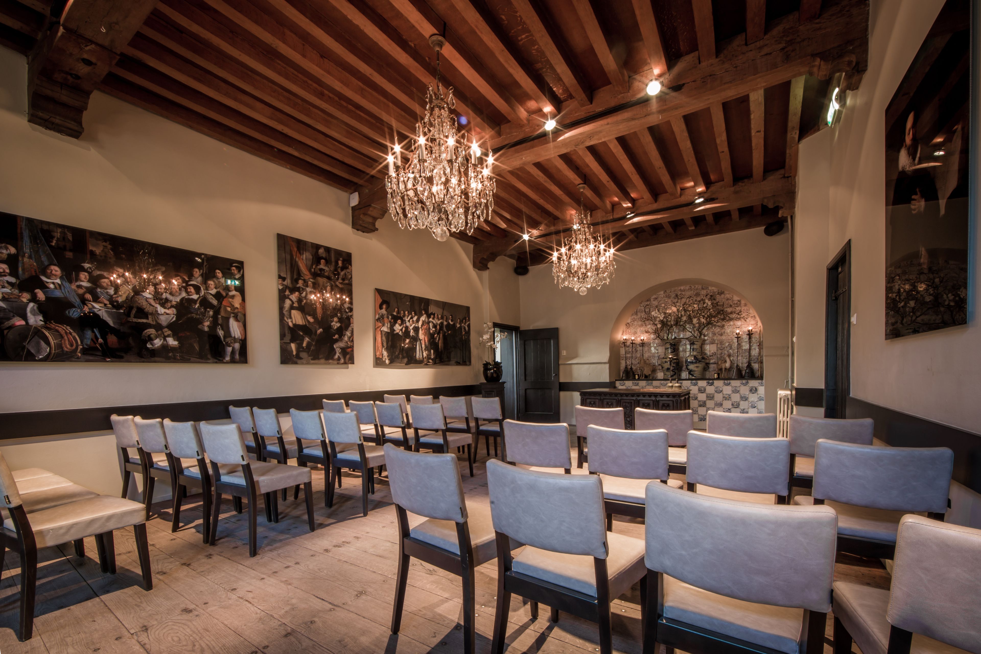 A dining area with wooden beams, chandeliers, and artwork on the walls.