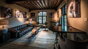 A cozy room with a leather sofa, wooden tables, and artwork on the walls. - Fletcher Landgoedhotel Renesse (Renesse)