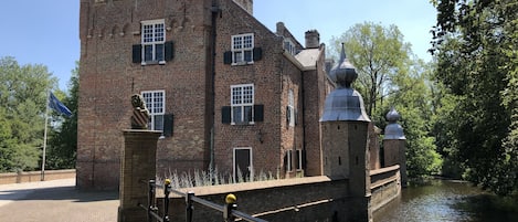 A historic brick building with a tower and domed roof, situated by a canal.