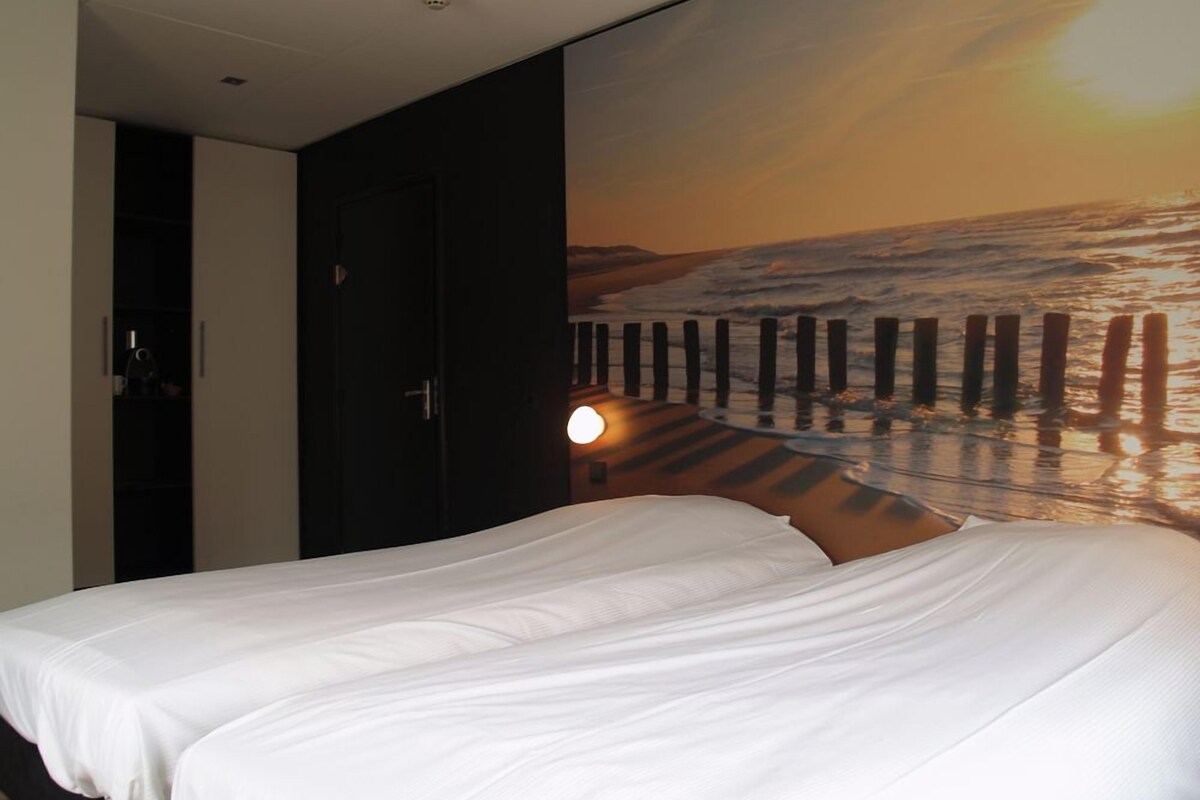 Un dormitorio con una cama, un armario y una pared con vistas al atardecer.
