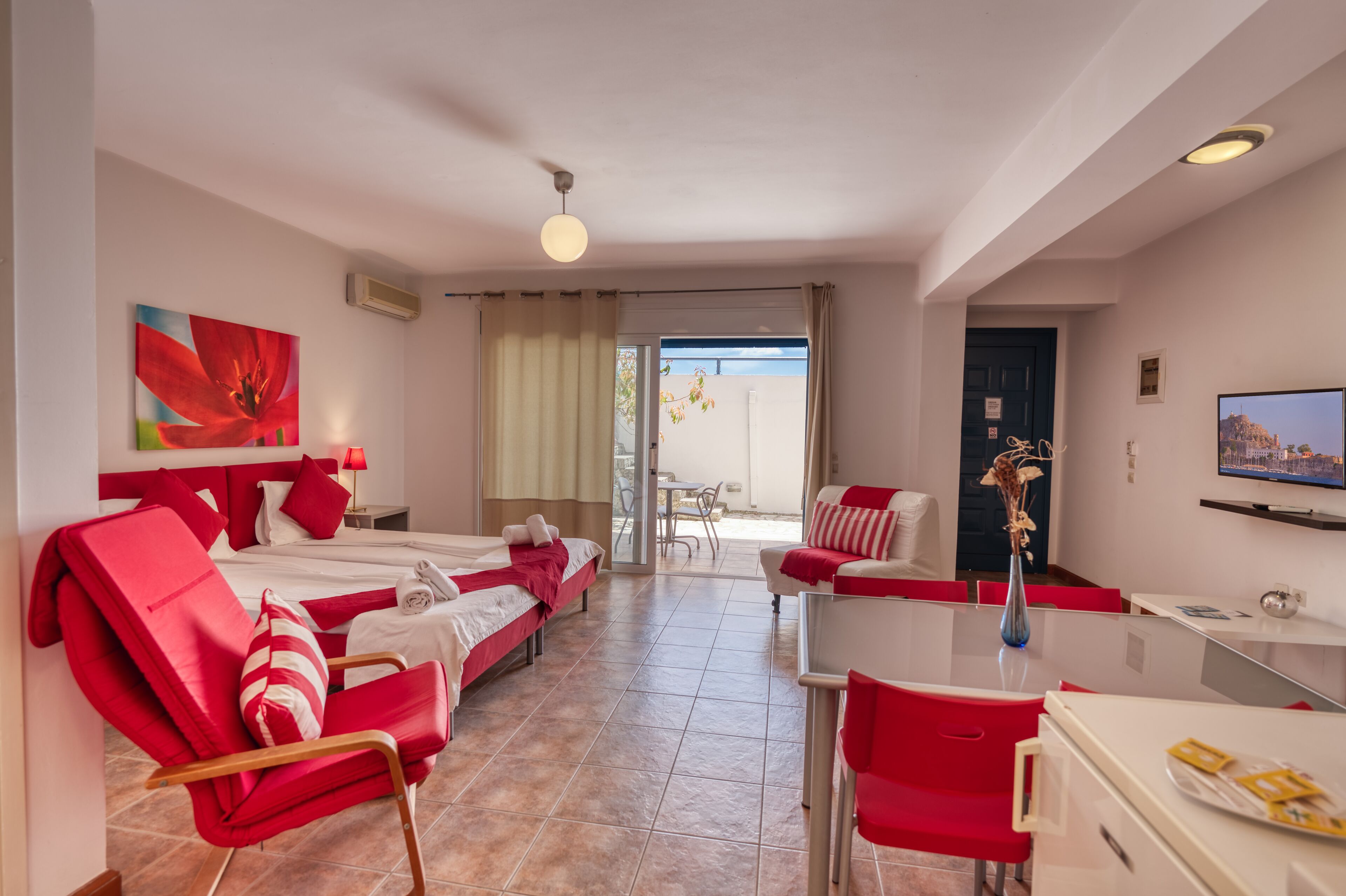 A hotel room with two beds, a dining area, and a TV.