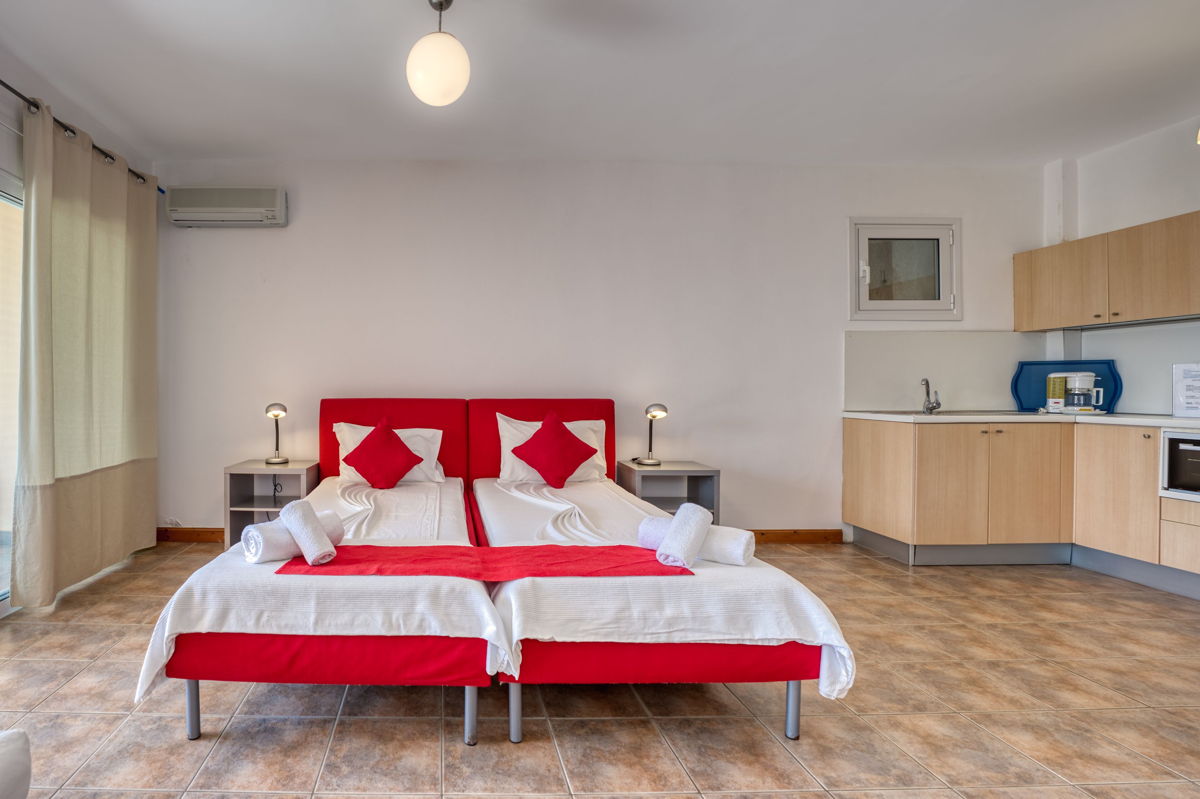 Una habitación de hotel con dos camas, kitchenette y baño.