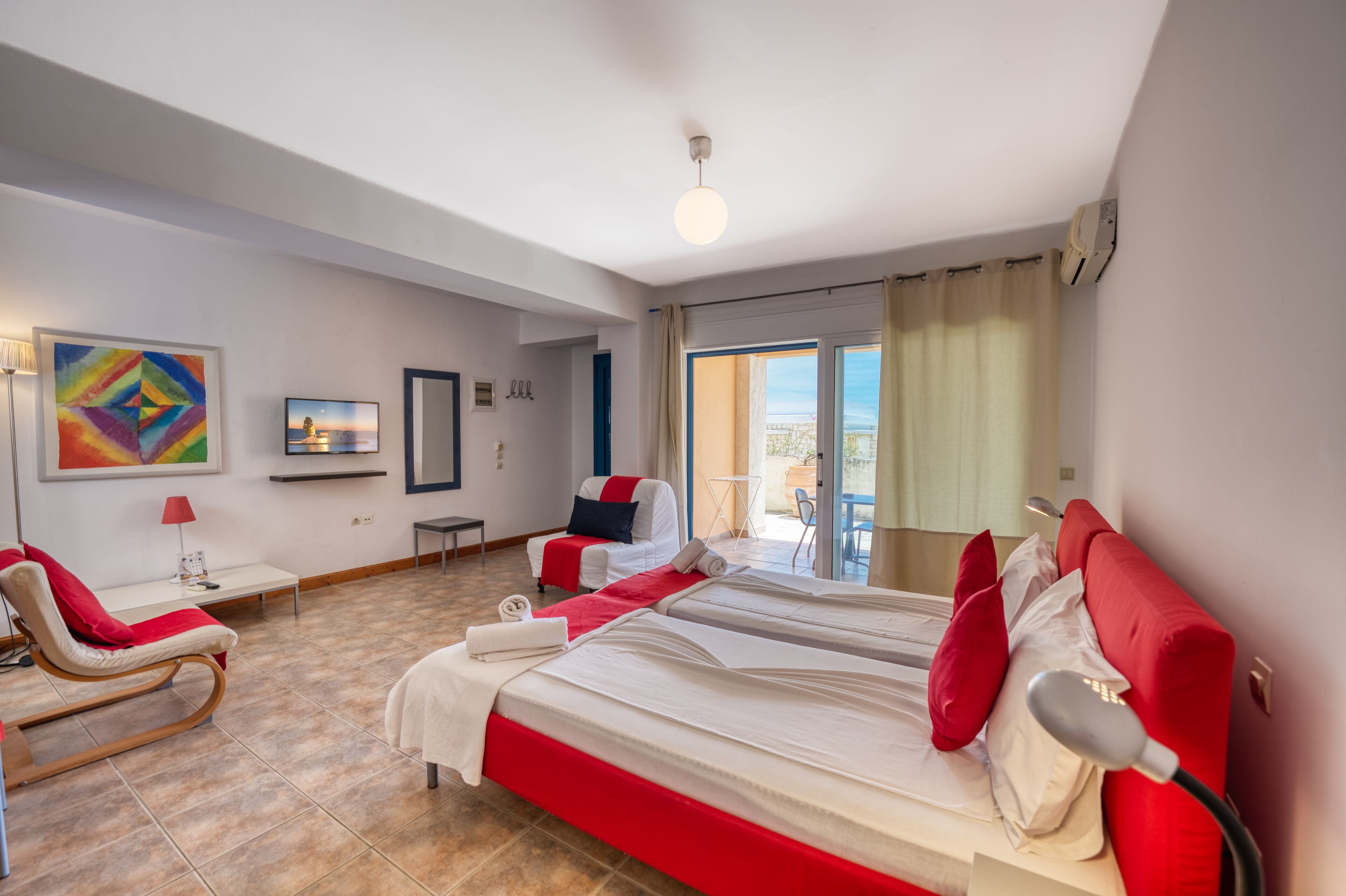A hotel room with a large bed, a chair, a small table, and a TV.
