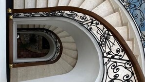 A spiral staircase with ornate black metal railings and a wooden handrail. - Hotel Castilla Real (Pereira)