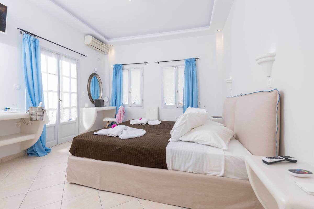 Una habitación de hotel moderna con una cama, una tocador con espejo, una bañera y una ventana con cortinas azules.