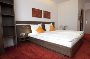 Un dormitorio moderno con cabecera de madera, alfombra roja y dos cuadros en la pared.