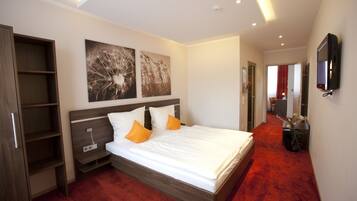 A modern bedroom with a large bed, wooden headboard, and a red carpet.