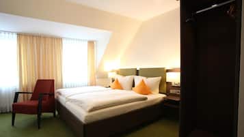 Una habitación de hotel con una cama, una silla, un armario y una ventana con cortinas.