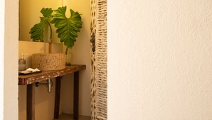 Une salle de bain avec un lavabo, un miroir, une plante et un rideau de douche.