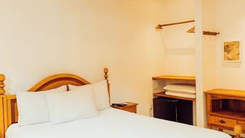 A neatly made bed with a wooden headboard, a bedside table, a nightstand, and a hanging light fixture.