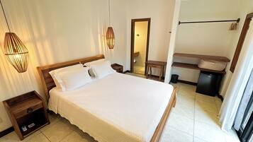 A neatly made bed in a hotel room with a wooden headboard, a bedside table, and a hanging light fixture.