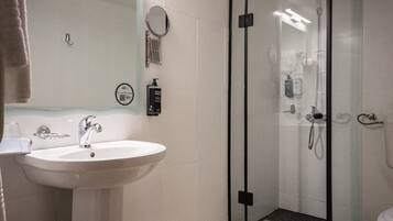 A modern bathroom with a glass-enclosed shower, a white sink, and a mirror.