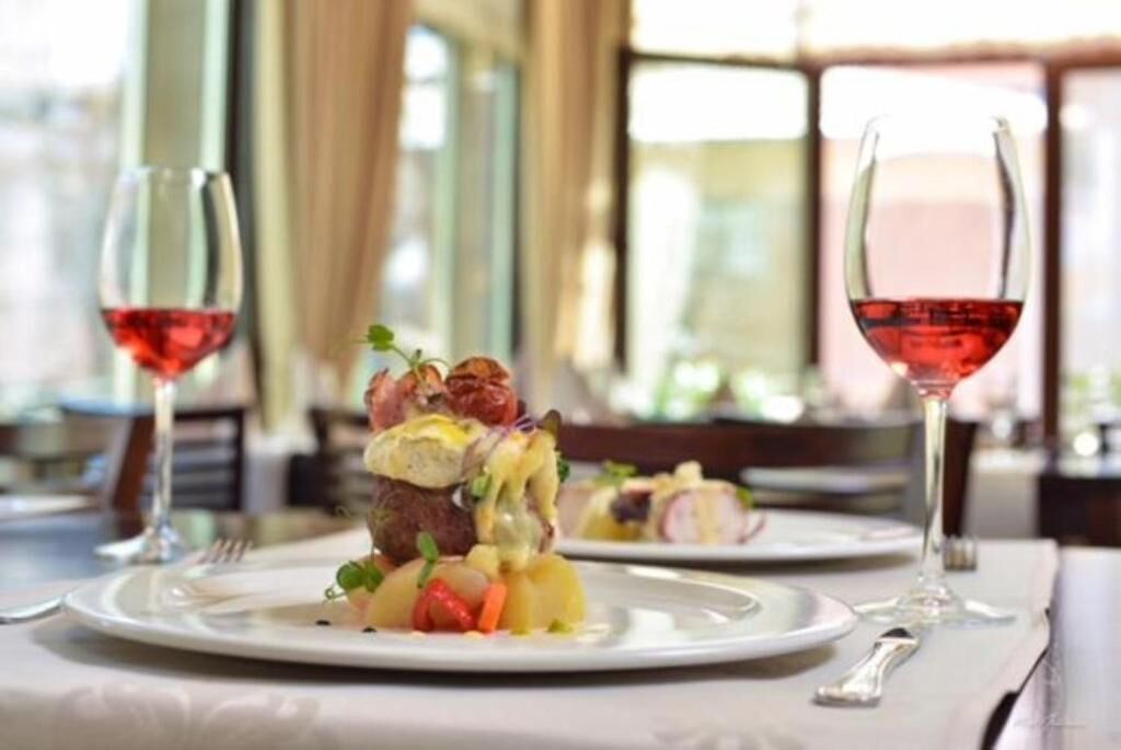 A dining table with plates of food and wine glasses.