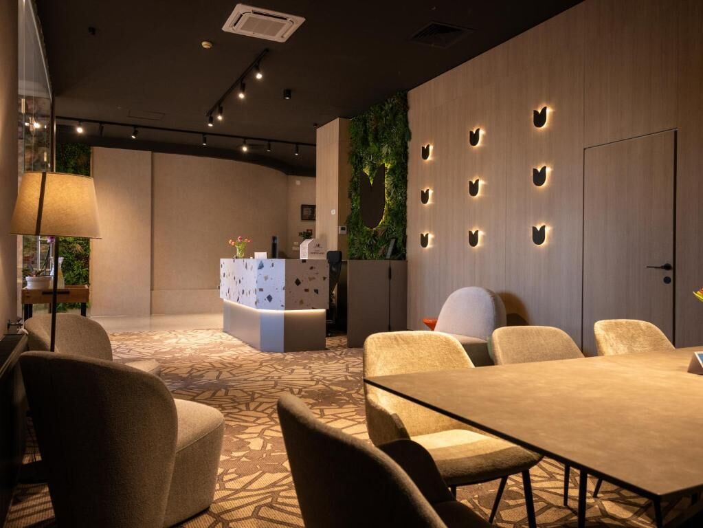 A modern hotel lobby with a reception desk, seating area, and a decorative wall with illuminated cutouts.