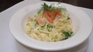 A white plate with a dish of pasta garnished with herbs and salmon.