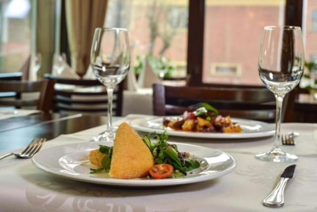 Une table à manger avec des assiettes remplies de nourriture, des verres à vin et des couverts.