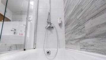 Un baño moderno con ducha de vidrio, una bañera independiente y un revestimiento de pared con diseño de mármol.