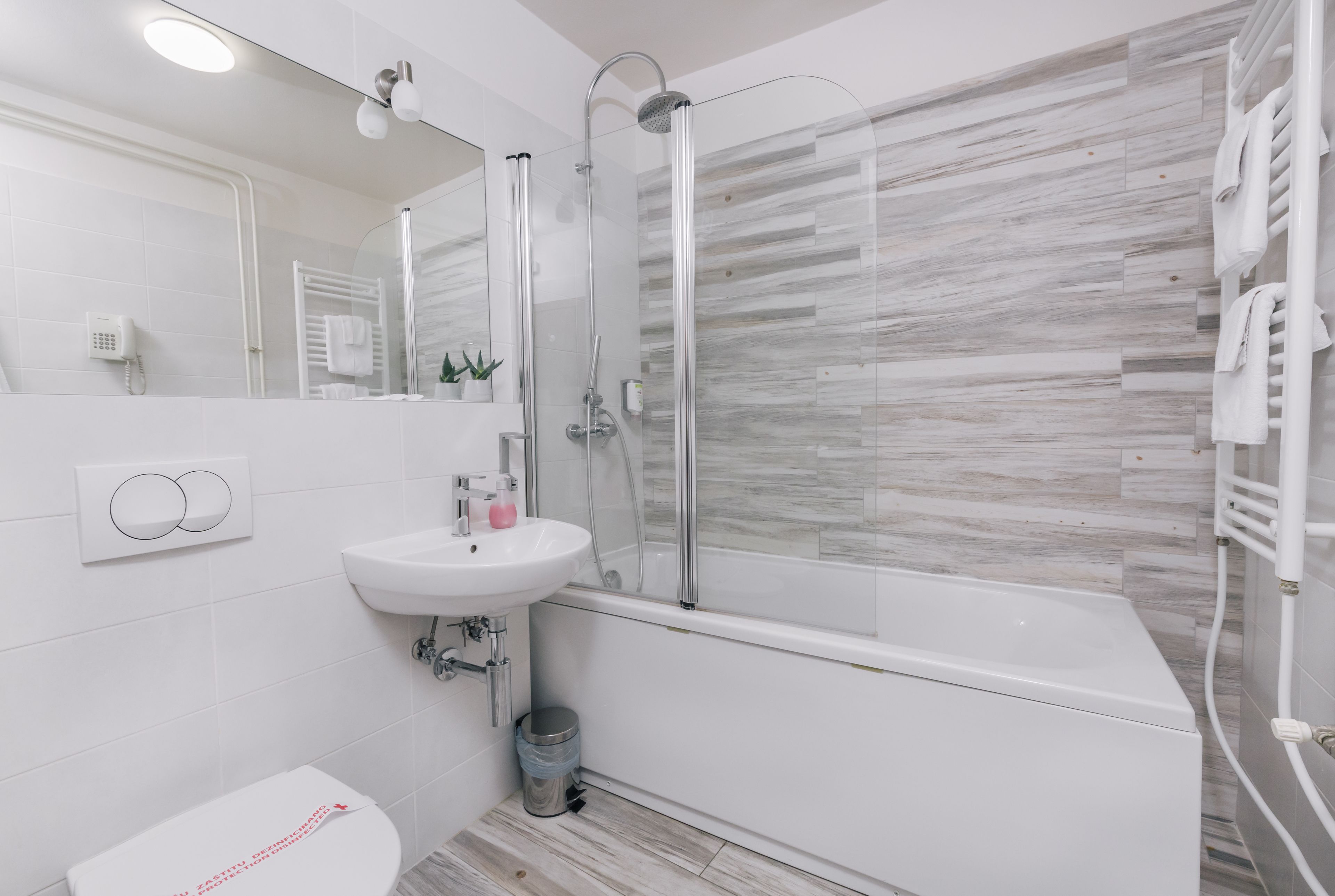Uma casa de banho moderna com chuveiro envolto em vidro, lavatório branco e sanita.
