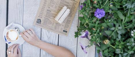 A menu on a wooden table with a cup of coffee and a spoon.