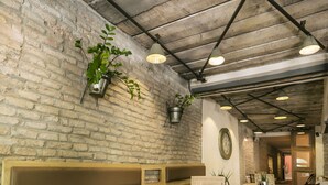 A restaurant with a long wooden table, multiple seating options including benches and chairs, a brick wall, and hanging pendant lights. - CitiHotel Veliki (Novi Sad)