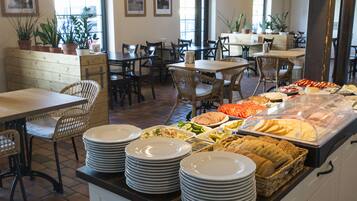 Un buffet proposant une variété de plats et où les assiettes sont empilées.