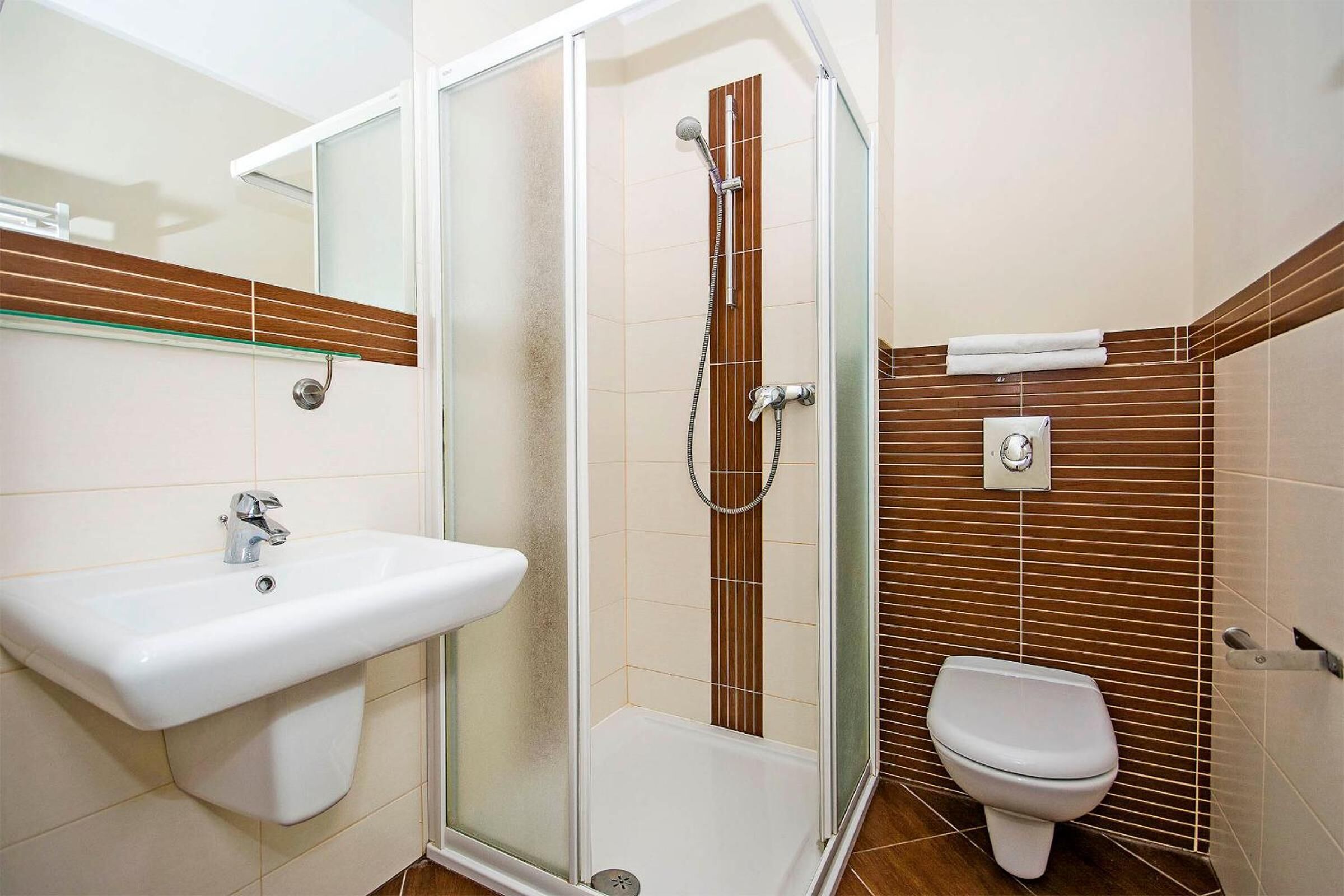 Ein modernes Badezimmer mit einer gläsernen Duschkabine, einem Waschbecken und einer Toilette.