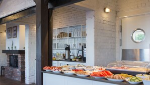 A buffet area with various food items and a brick fireplace. - Kurort Stara Wędzarnia (Gdansk)