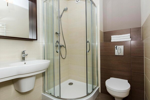Une salle de bain moderne avec une douche à parois de verre, un lavabo blanc et des toilettes.