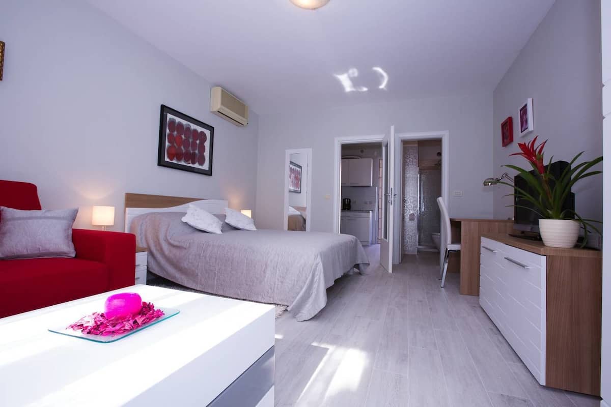 Una habitación de hotel moderna con cama, escritorio, silla, televisor y planta.