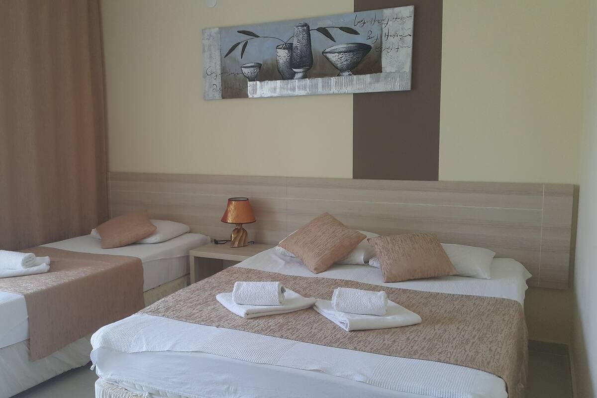 A hotel room with two beds, a nightstand with a lamp, and a painting on the wall.