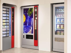 Three vending machines in a corner, each stocked with different items. - ibis budget Brussels Airport (Machelen)
