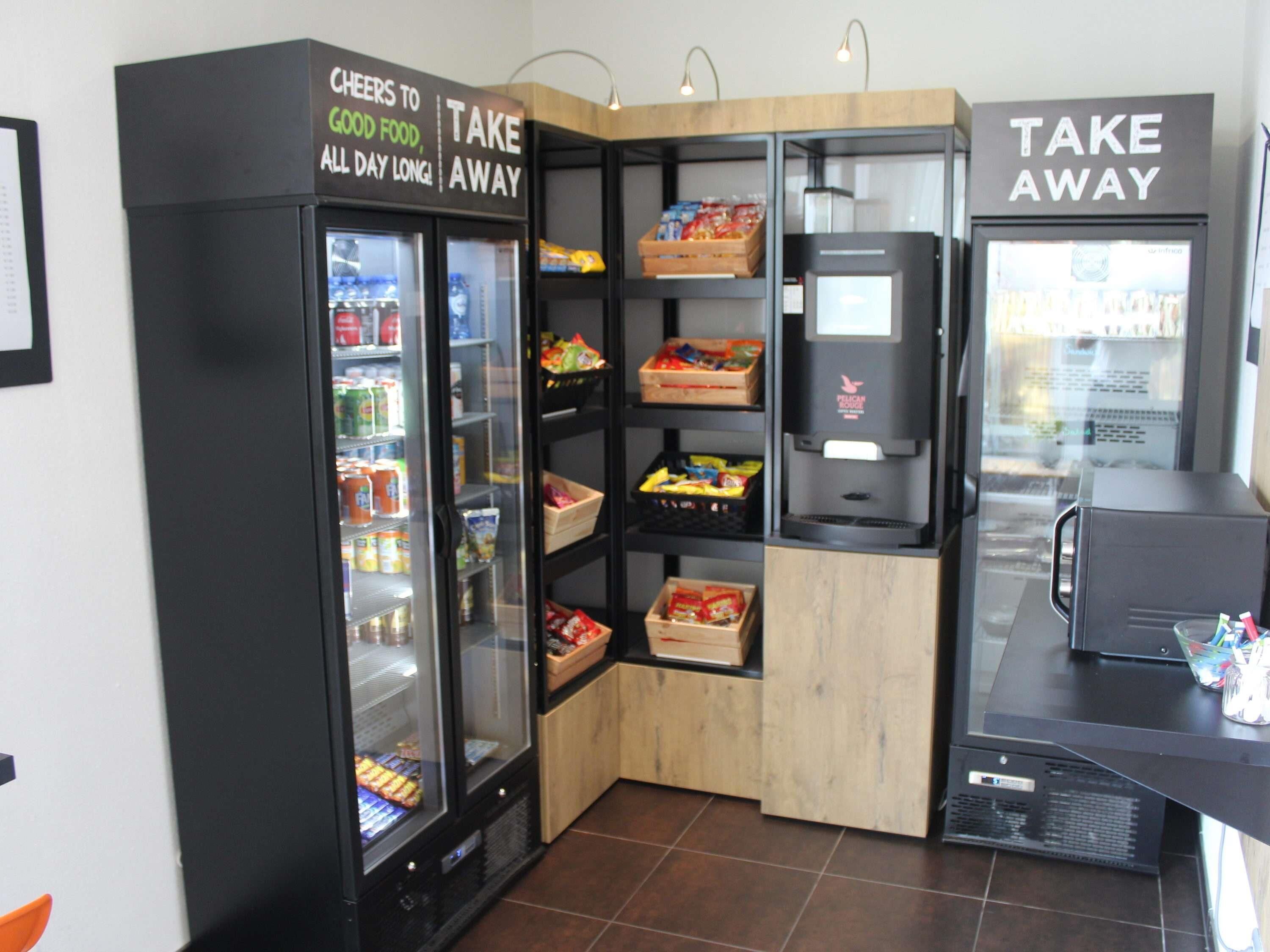 Um quiosque de autoatendimento com áreas refrigeradas e uma máquina de café.