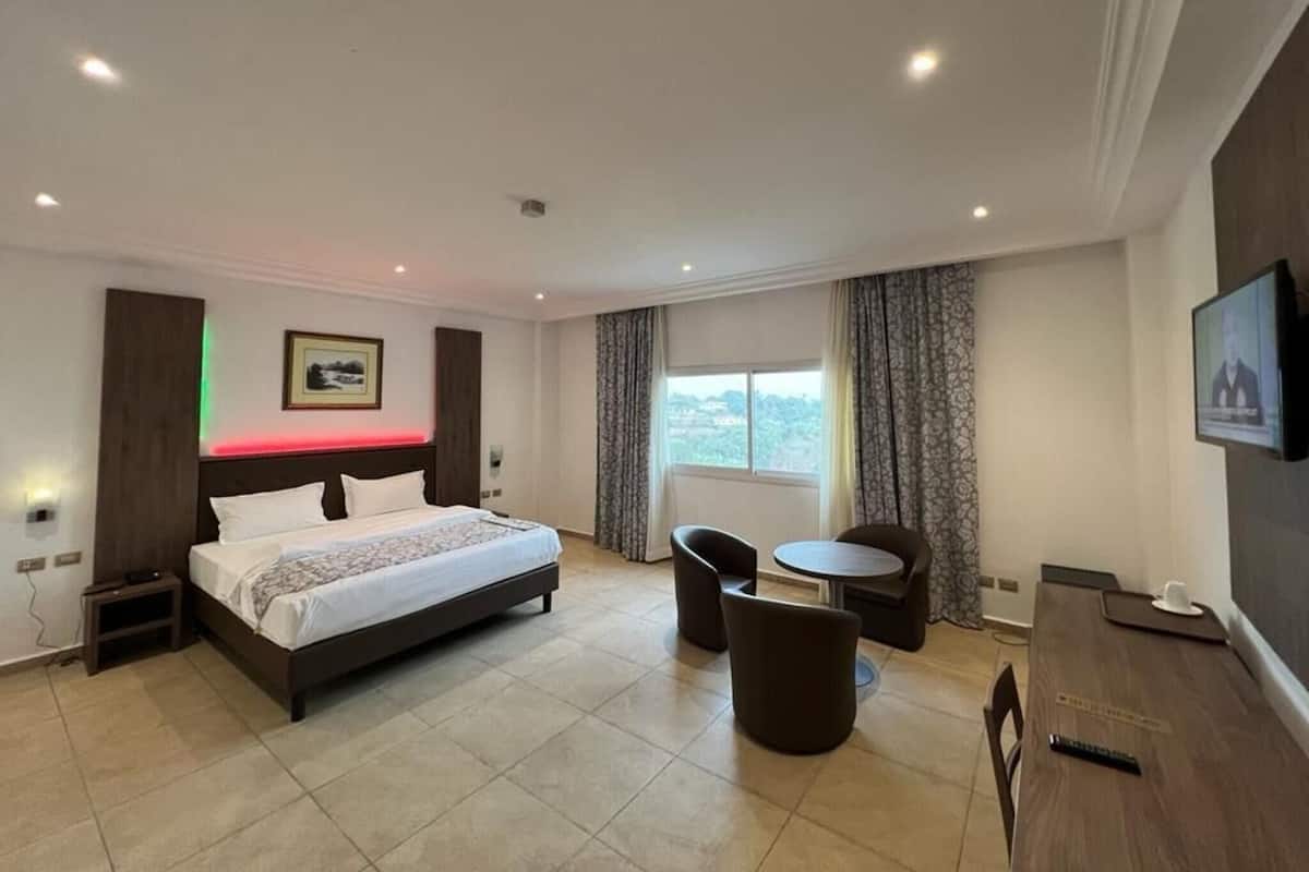 A hotel room with a bed, a desk, a chair, and a TV.