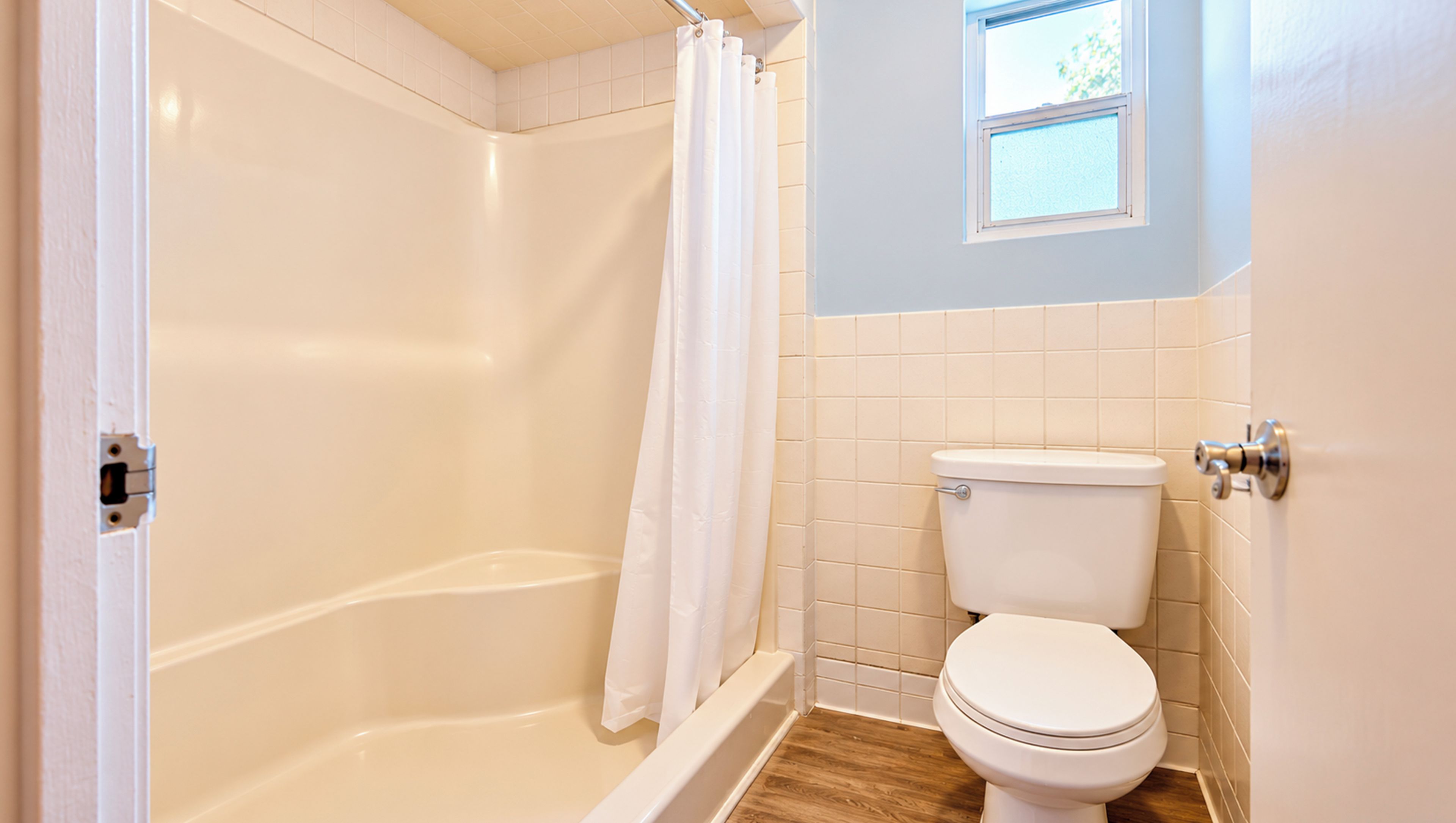 Un baño con bañera, inodoro y ventana.
