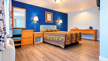 Un dormitorio con cama, mesitas de noche, cómoda, escritorio y espejo.