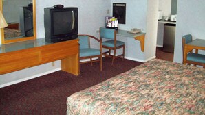 Une chambre d’hôtel équipée d’un lit, d’un bureau avec un téléphone, d’une chaise, d’une télévision et d’un réfrigérateur.