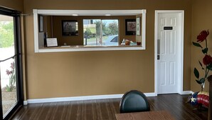 A reception area with a window, a reception desk, a door labeled "Employees Only," and a chair. - Glen Rose Inn and Suites (Glen Rose)