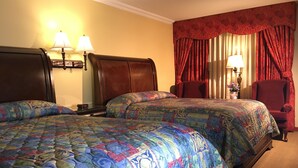 A hotel room with two beds, each with a patterned bedspread, a wooden headboard, a nightstand with a lamp, and a chair. - Acorn Motor Inn (Oak Harbor)