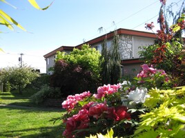 Un edificio residencial de fachada de piedra, rodeado de exuberante vegetación y plantas con flores.