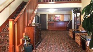 A spacious living area with a wooden staircase, a kitchen area, and a seating area with patterned upholstery. - Acorn Motor Inn (Oak Harbor)