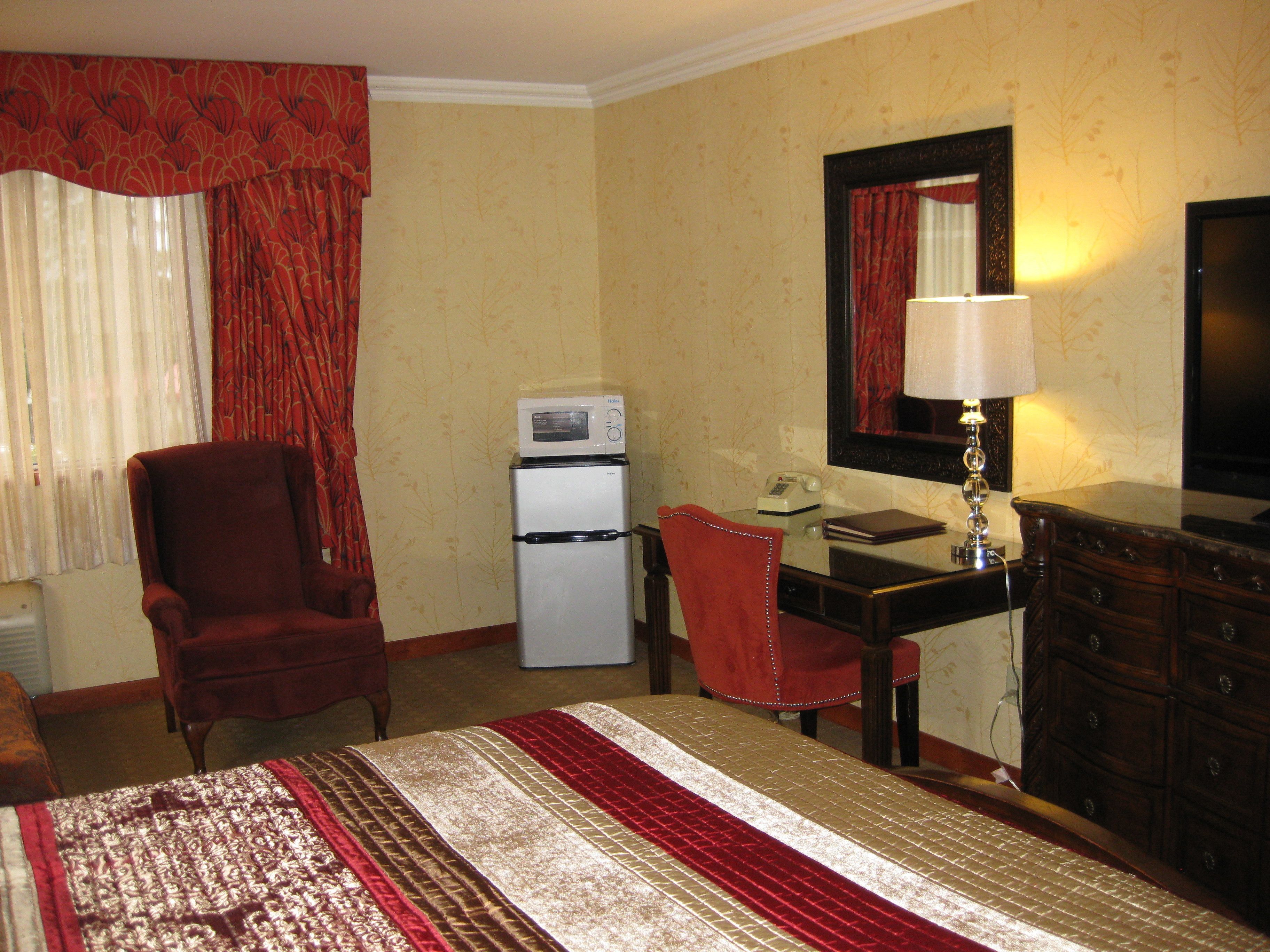 Une chambre d’hôtel comprenant un lit, un bureau avec un téléphone, un réfrigérateur, une chaise et une commode.