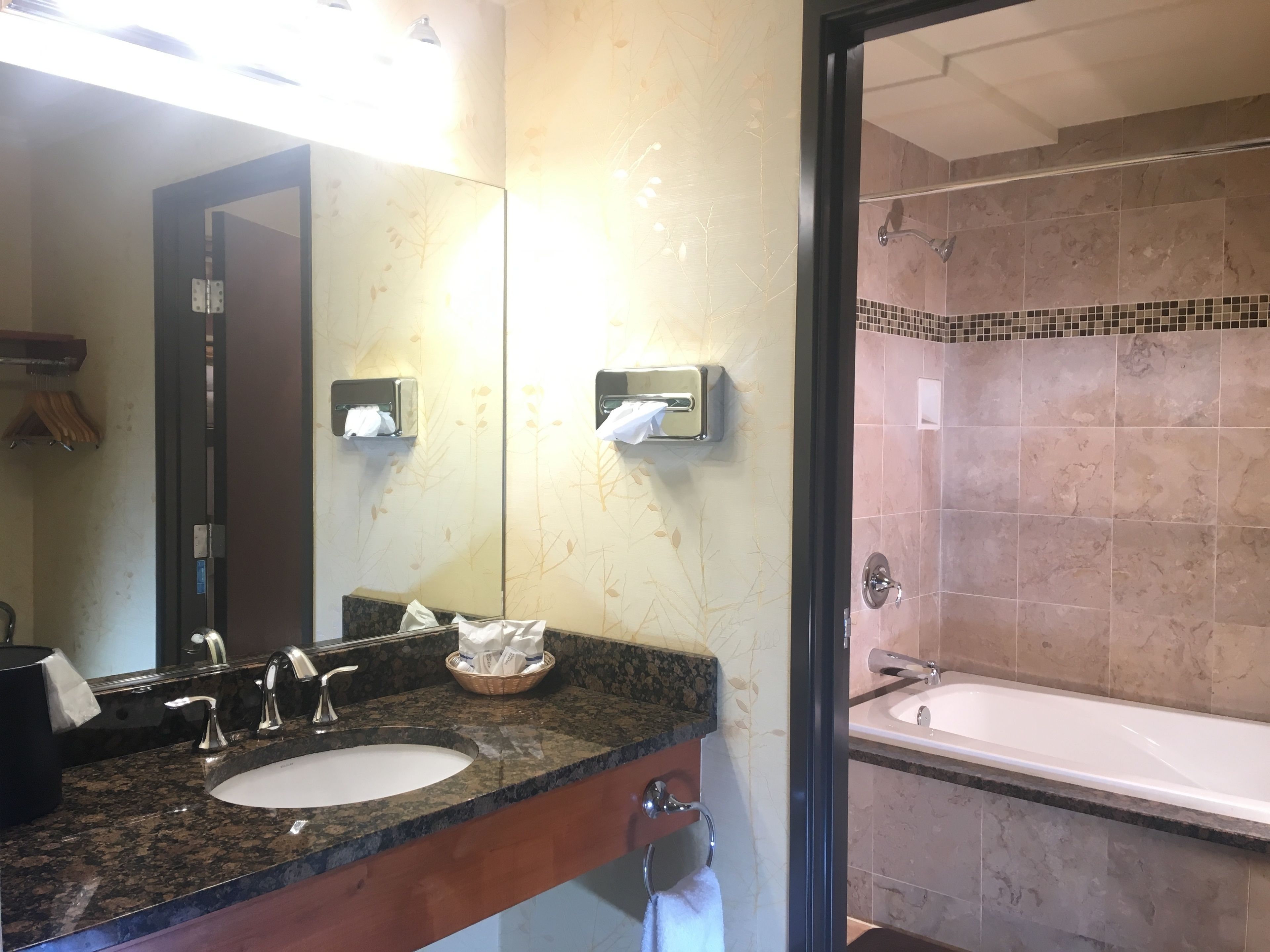 A bathroom with a sink, mirror, towel rack, and shower area.