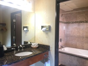 A bathroom with a sink, mirror, towel rack, and shower area.