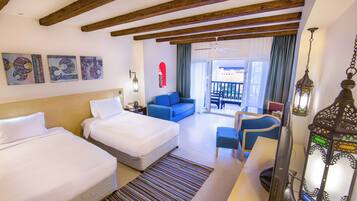 A hotel room with two beds, a sofa, a desk, and a view of the outside.