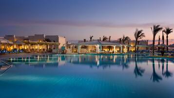 A pool area with lounge chairs and umbrellas, surrounded by buildings with distinct architectural features.