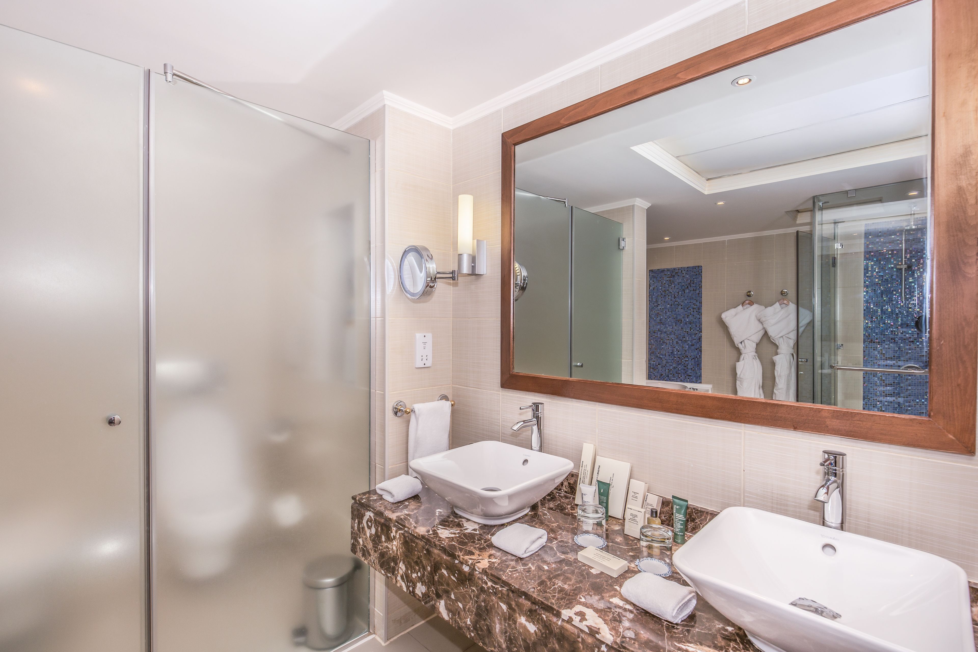 Un baño moderno con dos lavamanos, un espejo grande y una cabina de ducha de vidrio.