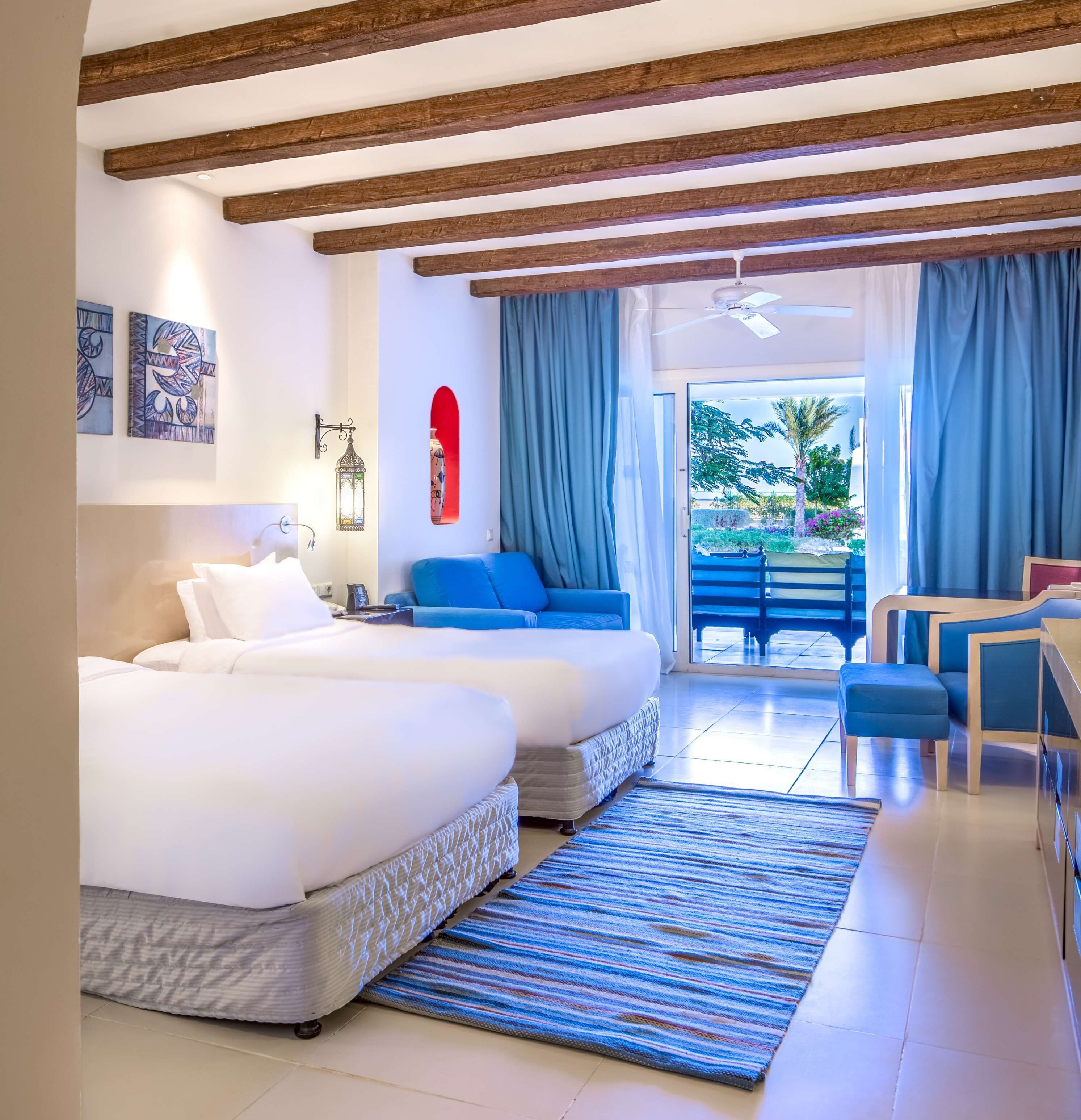 Een hotelkamer met twee bedden, een balkon en uitzicht op de omgeving.