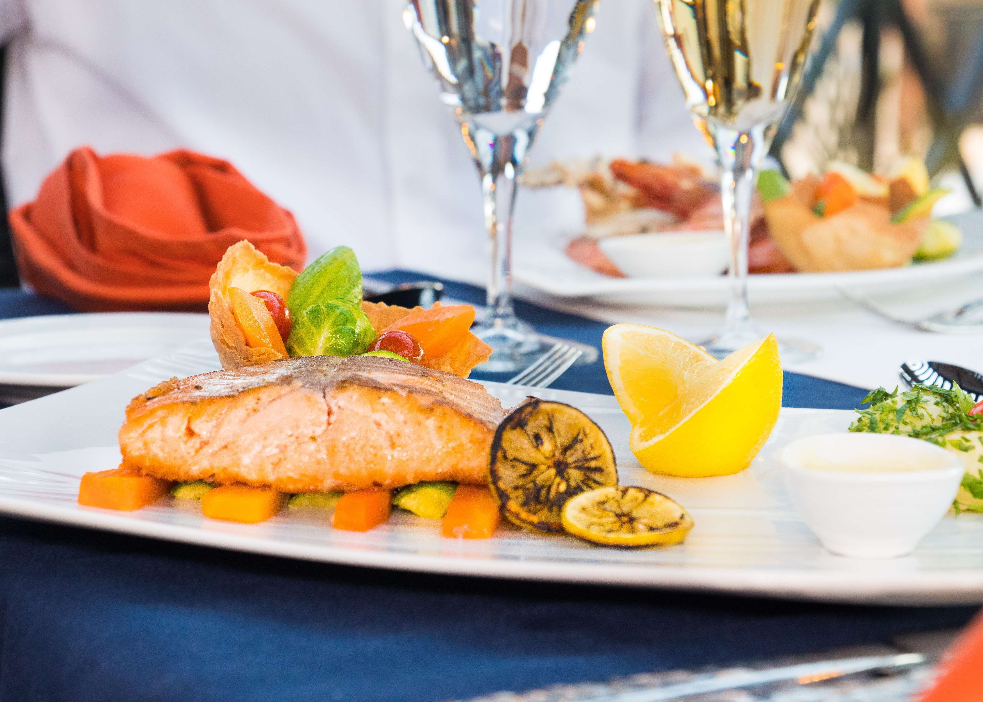 A plate of food with salmon, vegetables, and lemon slices.