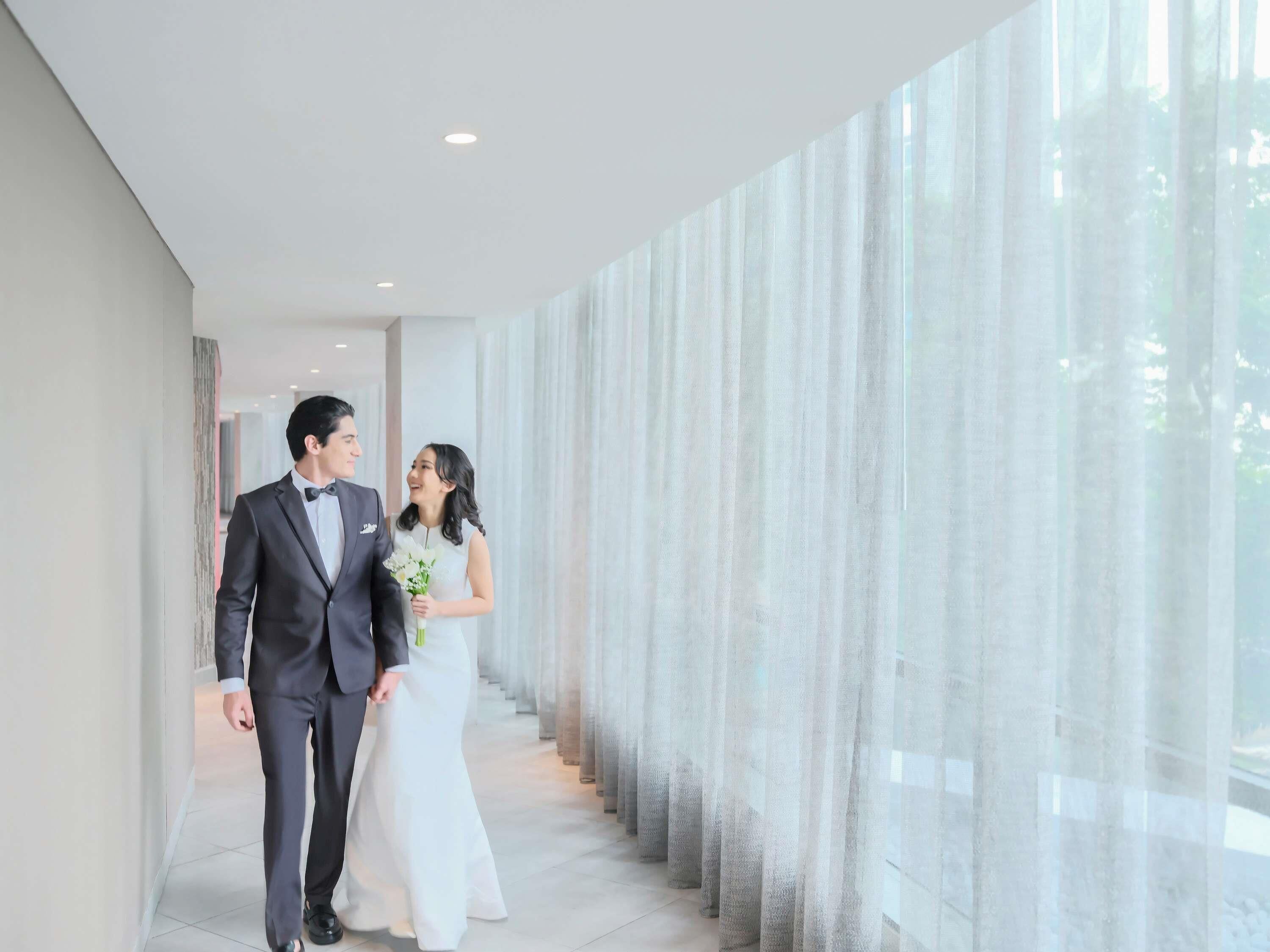 A modern hotel corridor with a glass wall and a row of vertical blinds.