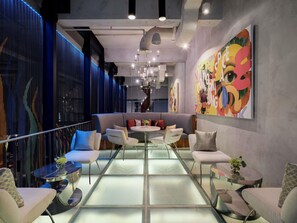 Un interior moderno con separador de vidrio, zona de estar y un mural colorido.
